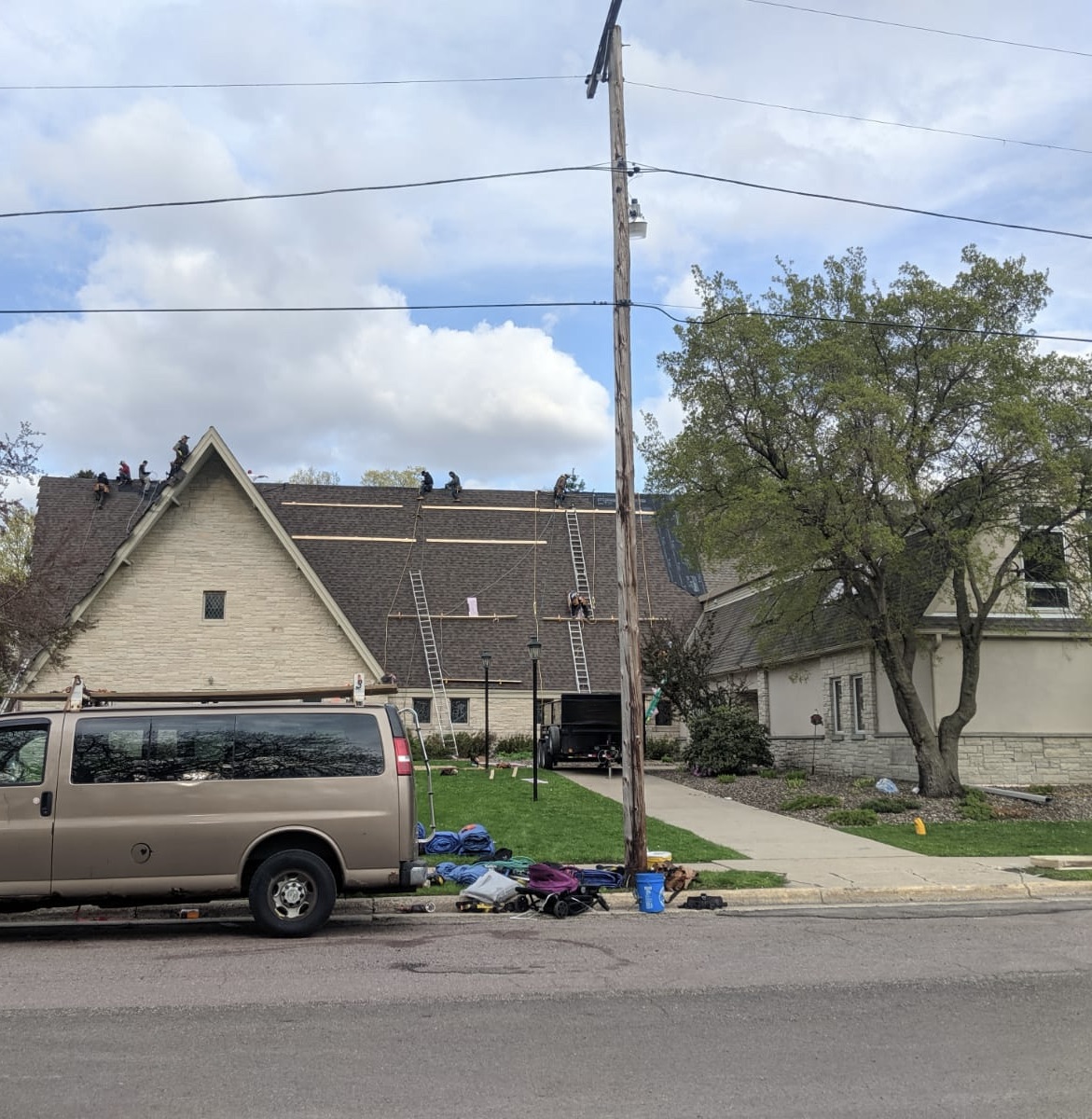 Full crew installing new shingles on a steep A-frame Twin Cities church roof