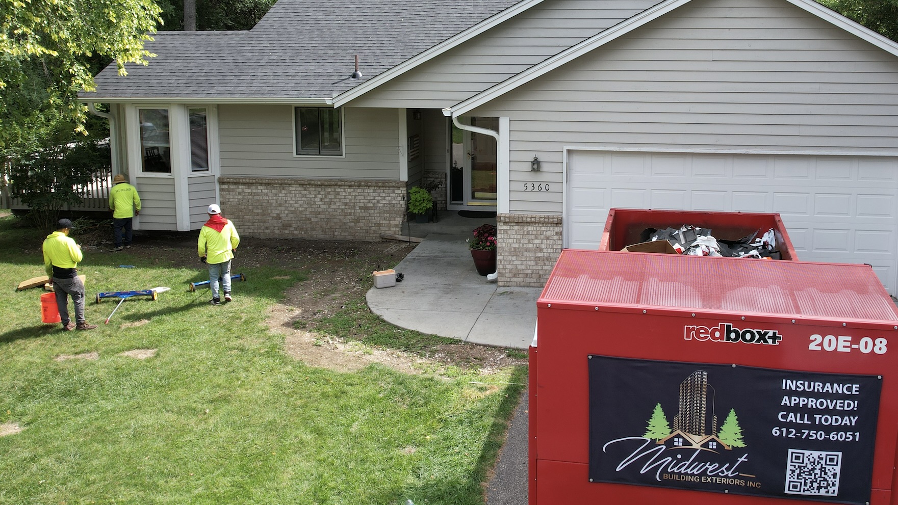 Midwest Building Exteriors crew completing a roof replacement in Roseville, MN with a redbox+ dumpster on site