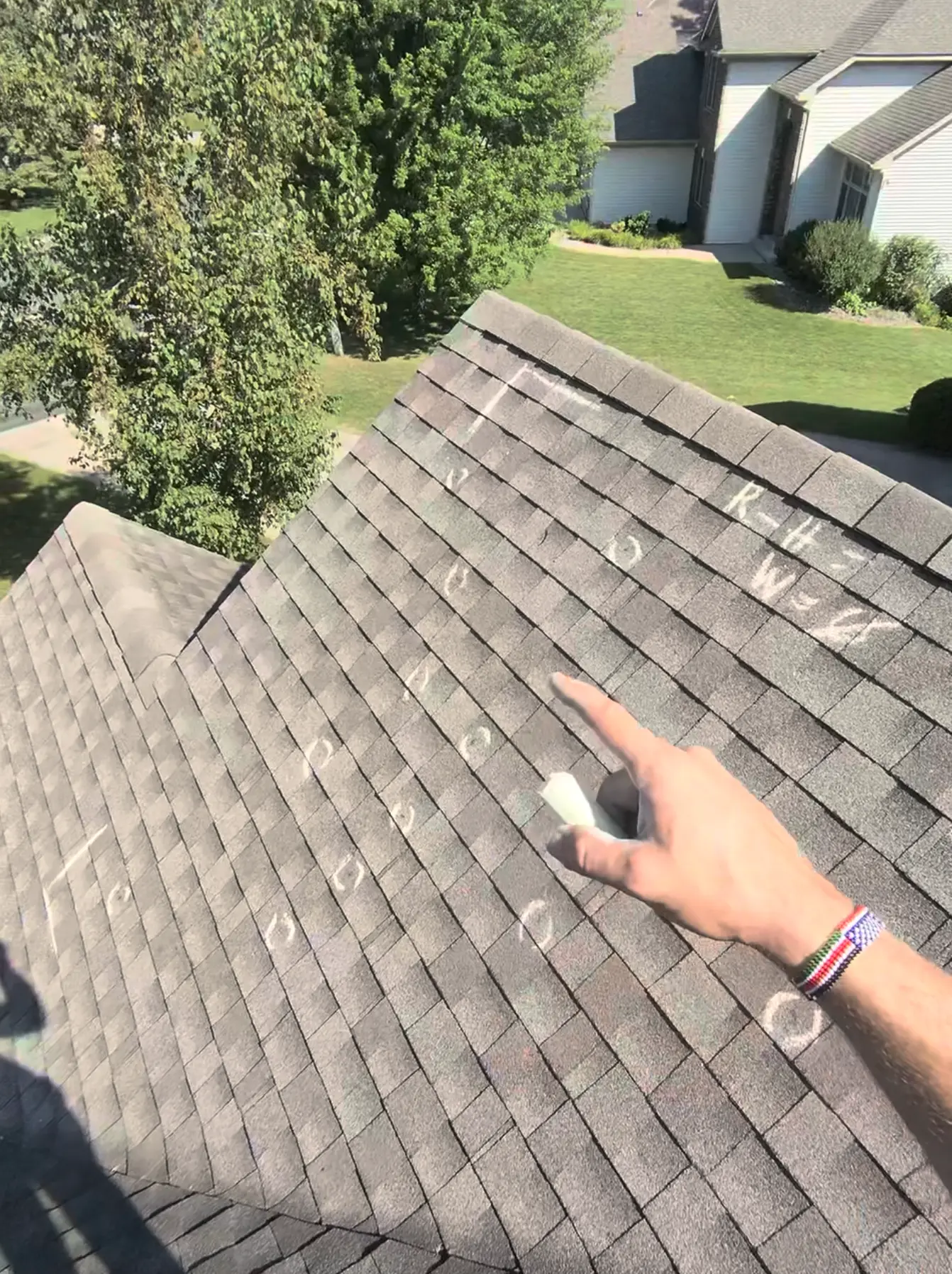 Roof inspector marking hail impact points with chalk circles on shingles in Roseville, MN