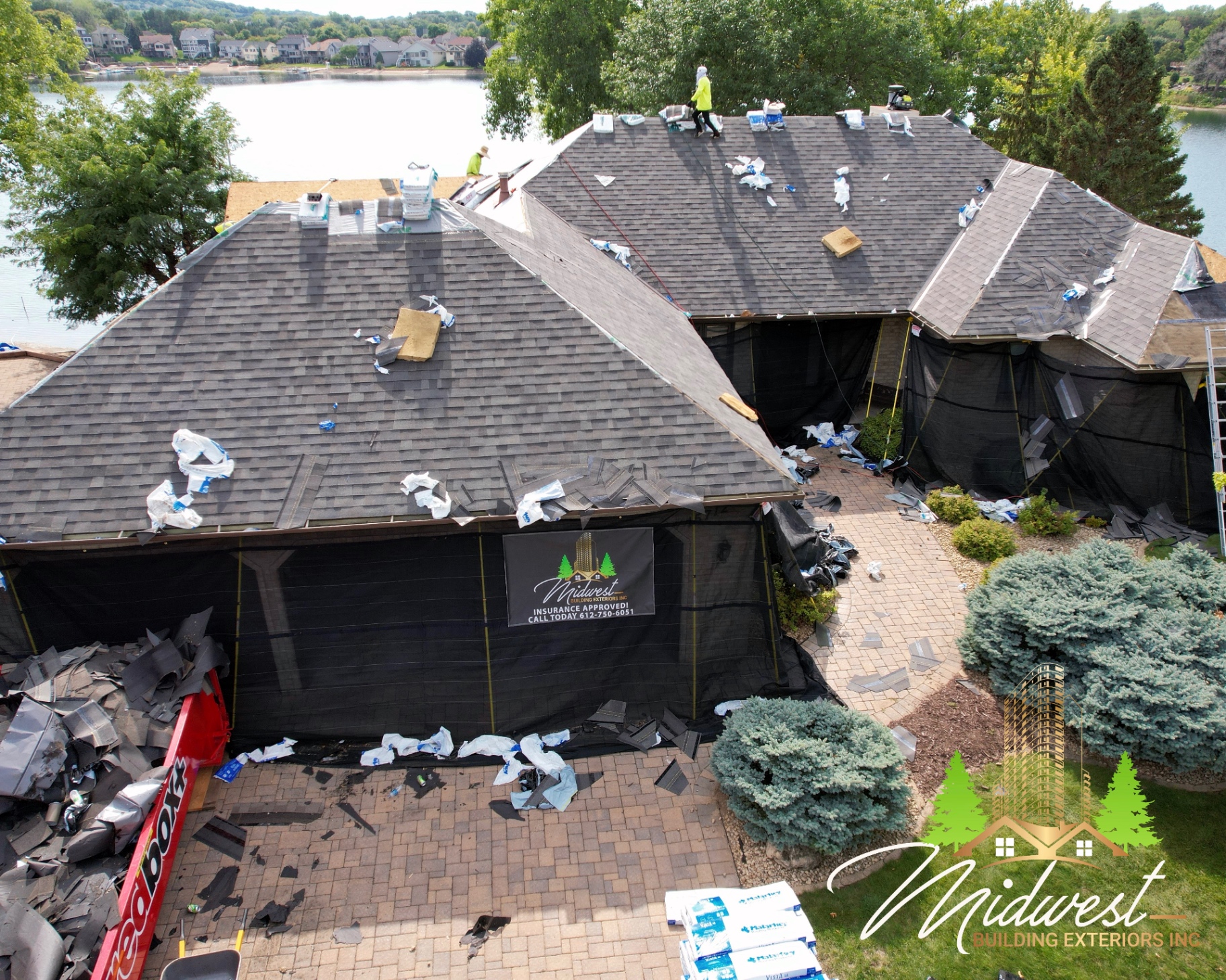 Roofing crew tearing off shingles on a lakeside home near Woodland, MN